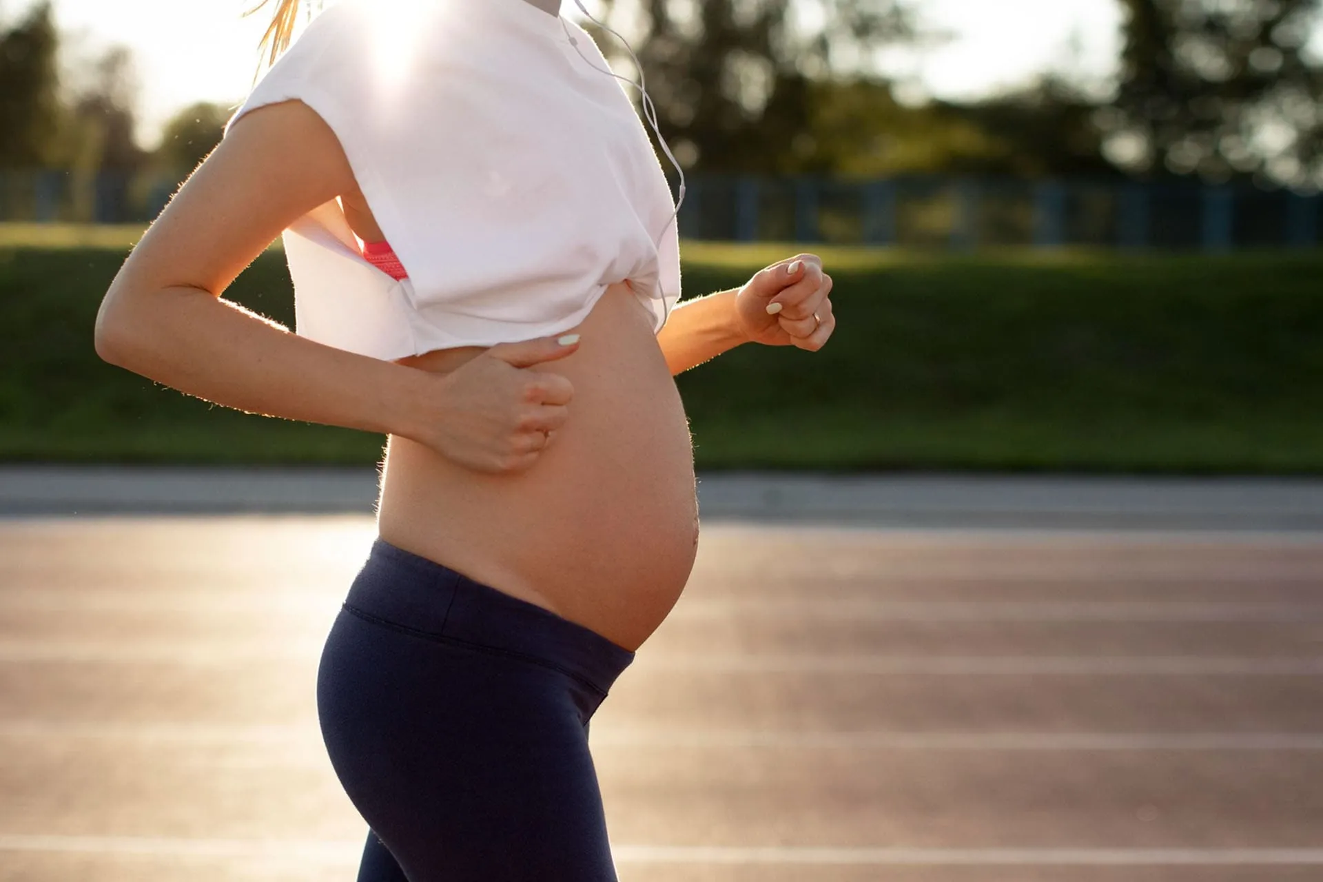 Gravid kvinna håller handen på magen under ett lugnt löppass