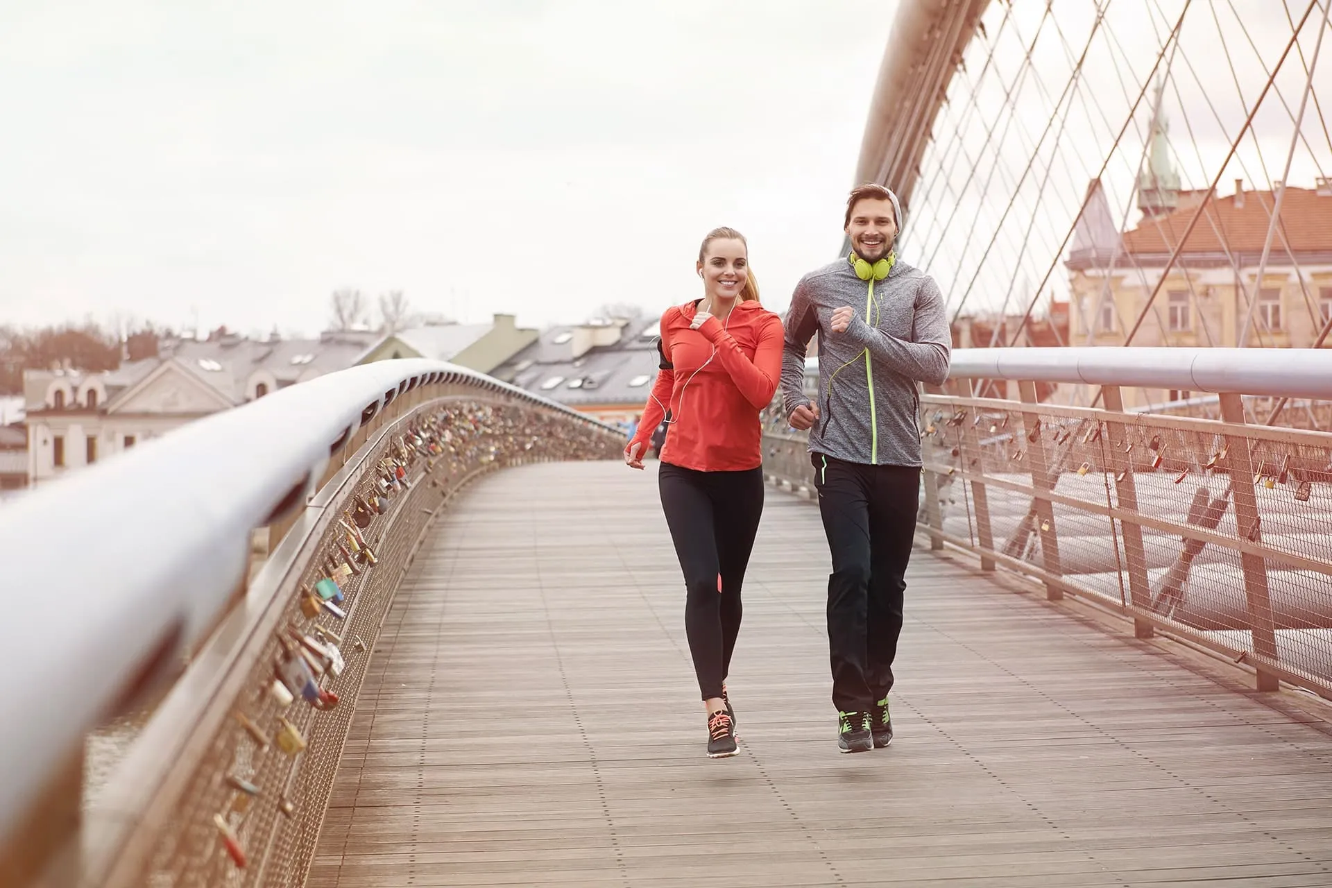 Kvinna och man joggar tillsammans över en gångbro