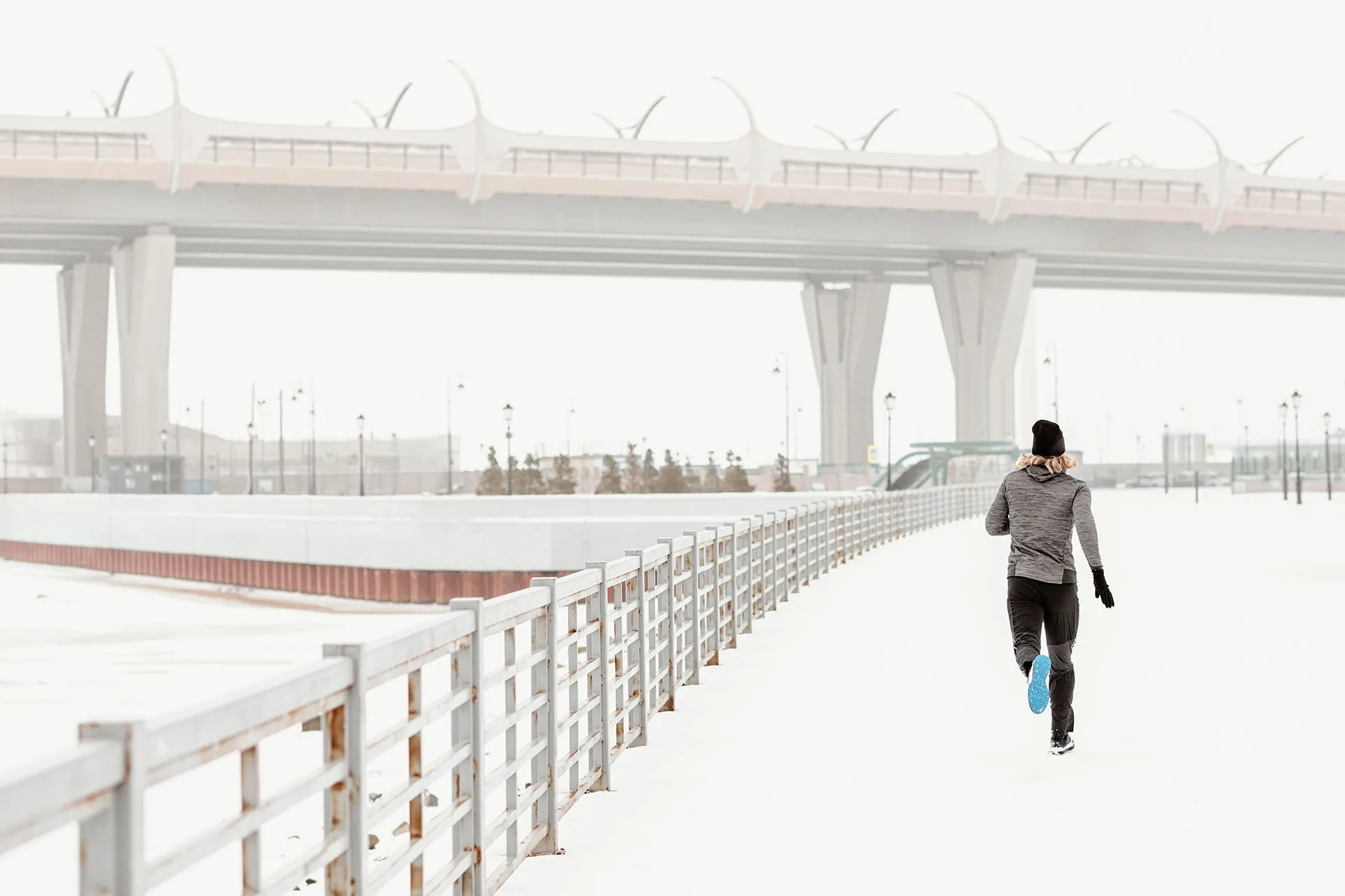 Löpare springer på en snötäckt gångväg en vinterdag